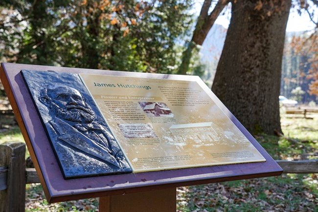Cerca de un camino se encuentra un cartel con un relieve palpable en bronce de un hombre.