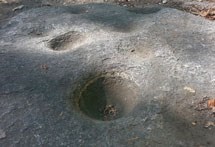 La luz del sol golpea depresiones en forma de cuenco que fueron golpeadas en la roca de granito.