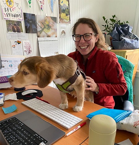 Yosemite Conservancy communications intern working at a computer with a dog on the desk