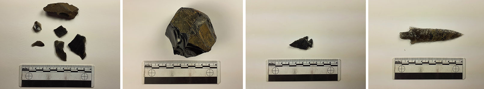Obsidian fragments, chunk, and projectile points in varying sizes.