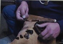 Man using a knapping technique to make projectile points.