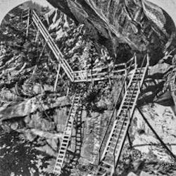 Ladders and platforms against a rock cliff.
