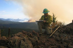 A firefighter studies his journal with smoke behind him