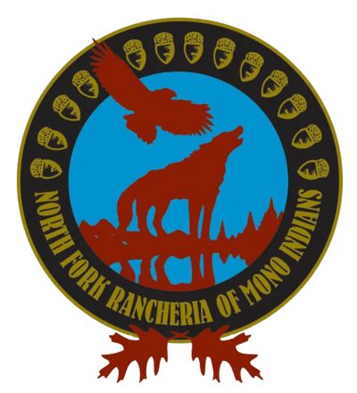 A graphic of a round blue seal with a red eagle and howling wolf in front of a mountain range. The seal is surrounded by a gold-yellow border of acorns and the name, "North Fork Rancheria of Mono Indians," with a pair of red oak leaves at the bottom.