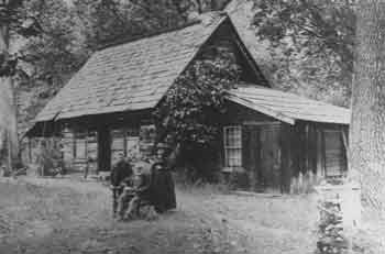 Family poses in front of historic cabin