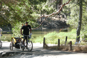 People biking along the Merced with someone floating in a raft on the river.