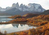 Ragged peaks rise behind a river with fall colors