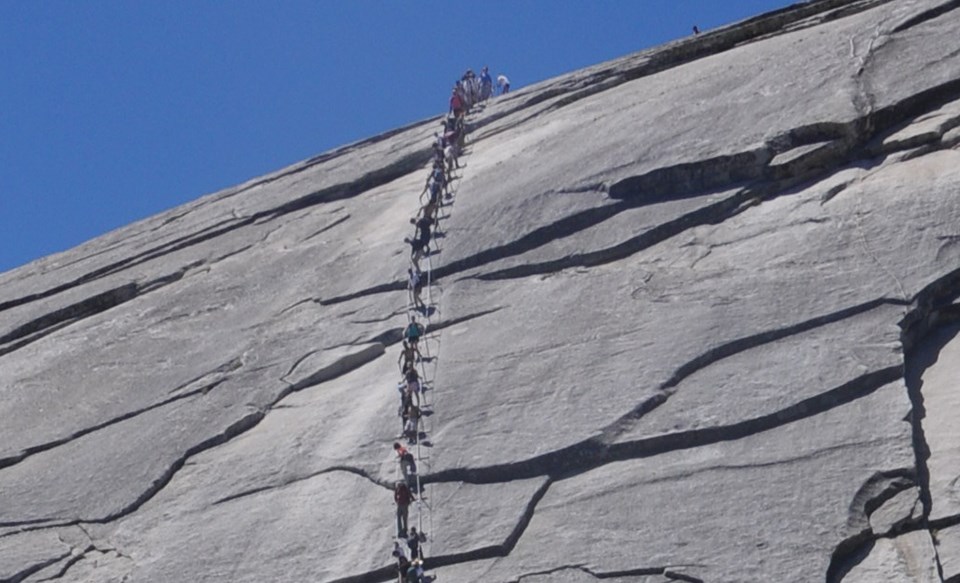 Upper section of Half Dome cables with people climbing up and down