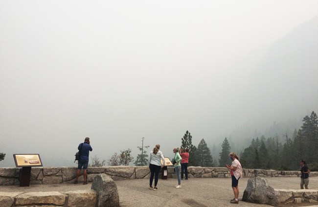 Tourists stand in front of smoke-obscured viewpoint
