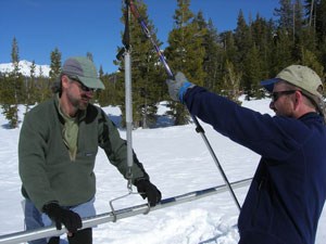Two rangers hold an aluminum tube