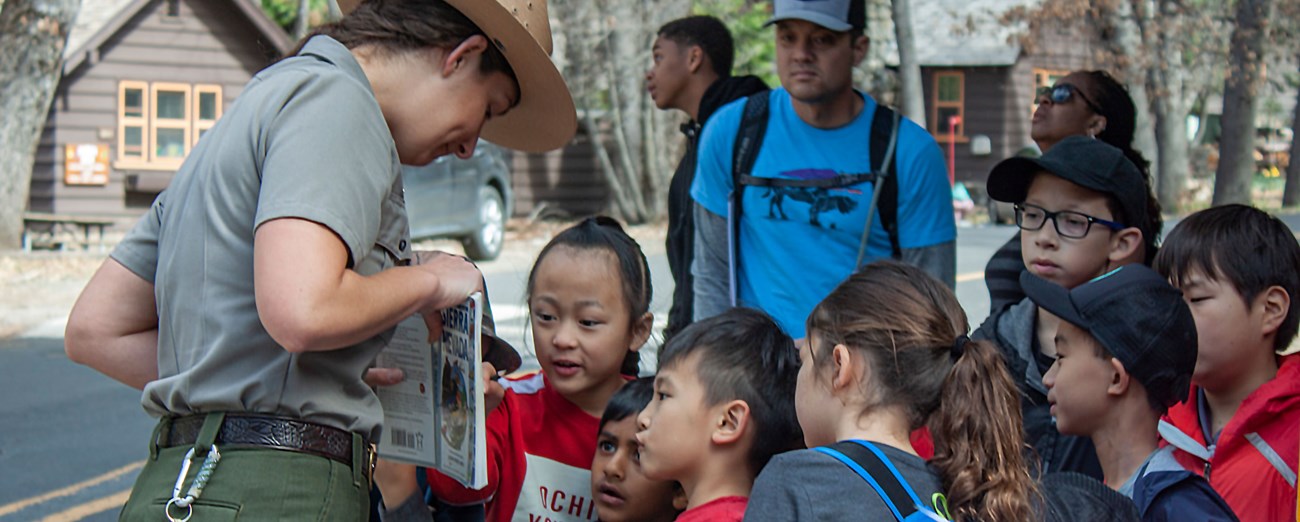 A ranger shows a field guide to a group of small children.