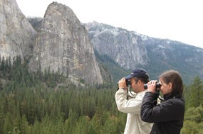 Two people hold binoculars to face while birding