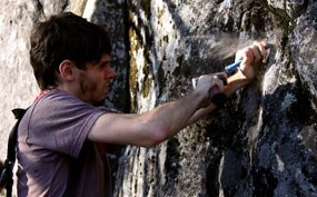 Scientist chisels rock to collect lichen sample