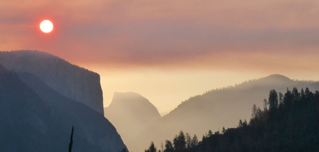 Sun turned orange by smoke over El Capitan and Half Dome