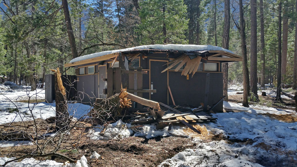 Restroom building damaged by trees