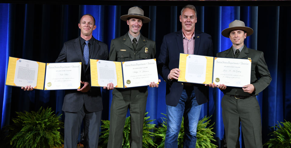 Left-to-Right_Nick-Bliss,-Philip-N.-Johnson,-and-Jesse-McGahey_73rd-Honor-Award-Convocation-Ceremony_Photo-Credit-Department-of-the-Interior Three rangers and the Interior secretary on stage displaying award certificates