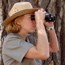 Ranger looking through binoculars while out in the field.