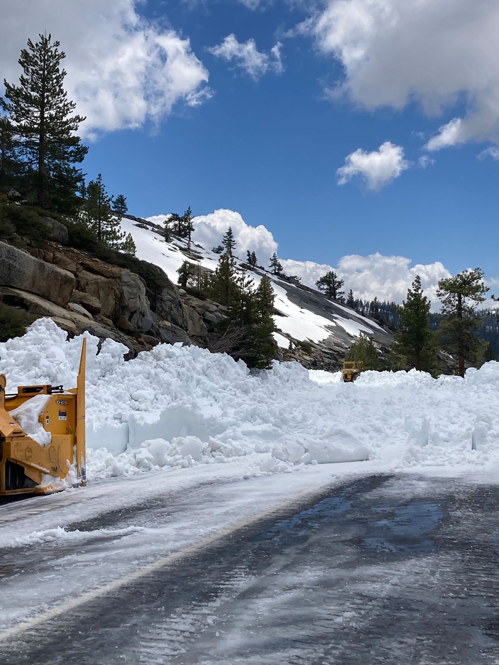 Blower plow pushing through piles of snow moved by the dozer (in the far distance in the snow)