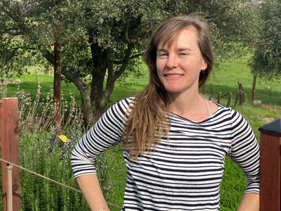 Headshot of a woman with blonde hair standing by a tree
