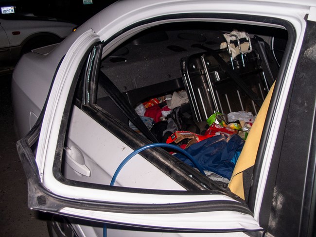 Car with windowframe pullled down and back seat pulled out for food in trunk