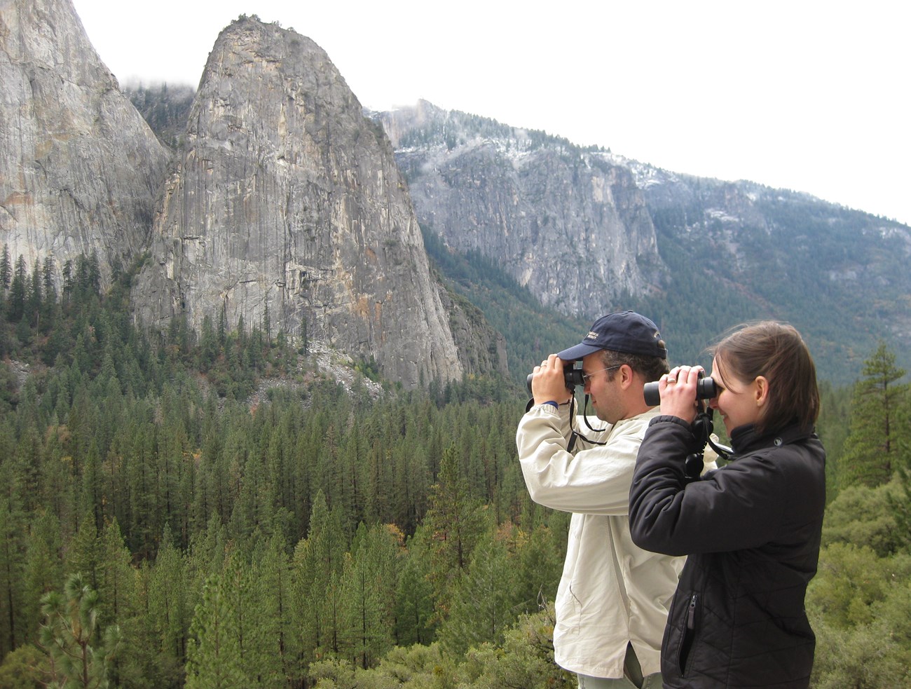 Two people with binoculars birding above Yosemite Valley.