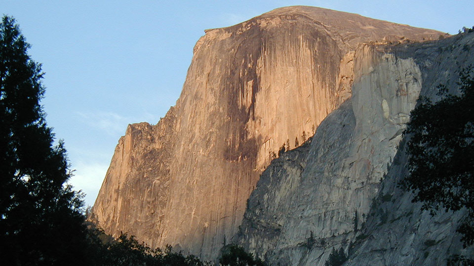 A picture of a large, flat faced mountain at sunset.