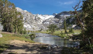 Alpine meadows below snow-covered mountains along the John Muir Trail