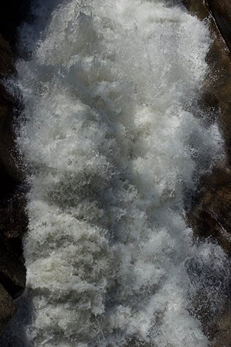 Rushing waterfall flowing over granite cliffs.