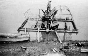Historic photo of two people tending a fish wheel on the Yukon River.
