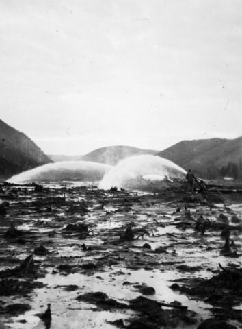 Spraying water using hydraulic giants to thaw frozen ground.