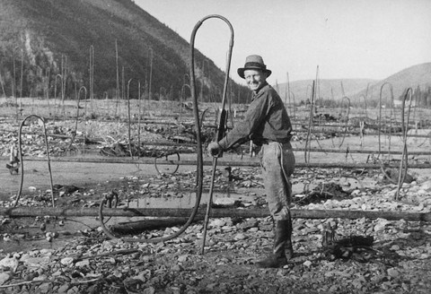 Dredge worker thawing with steam points, ca. 1935.