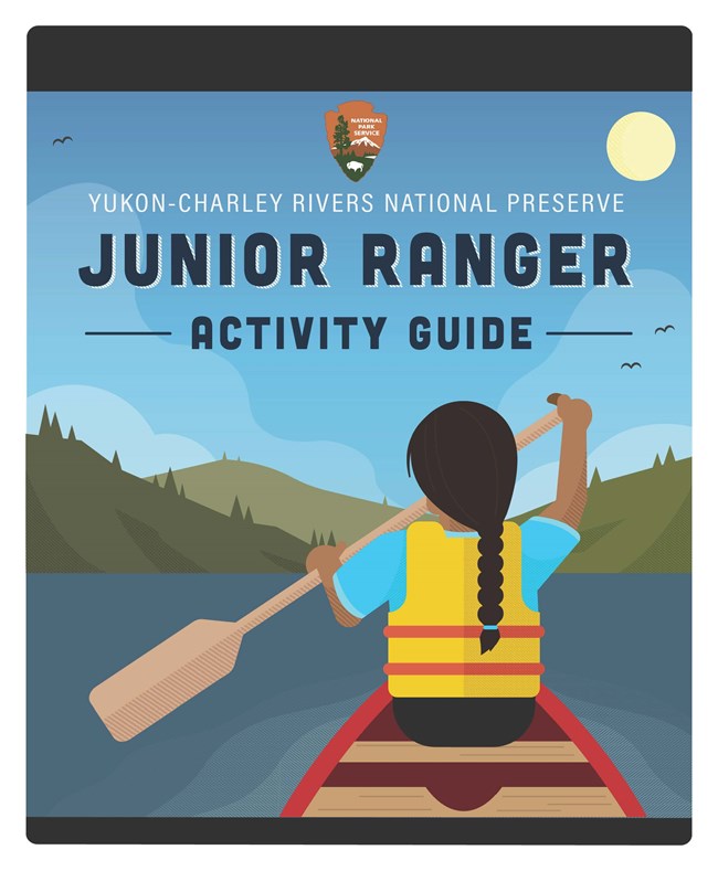 Cover of Yukon-Charley Rivers National Preserve Junior Ranger Activity Guide. Illustration shows rear view of girl paddling in the front of a canoe, with blue sky and green hills in the background.