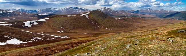Panoramic photo of mountains with patches of snow
