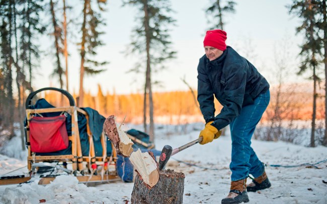 A man splitting firewood in winter