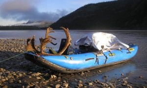 Caribou rack and game bags on a raft on a river bank