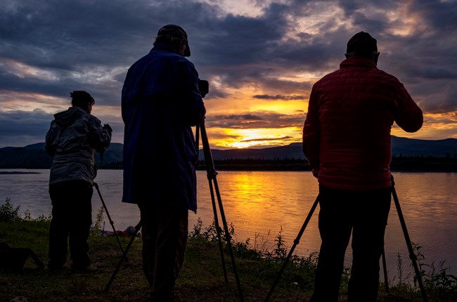 Three photographers photograph sunset over the Yukon River