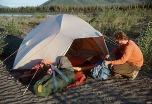 A camper sets up on a gravel bar.