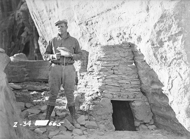 Person with archeology tools stands next to an area they are studying.