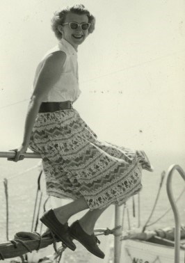 Young woman in a white dress, seated on handrail of a boat, while visiting Italy