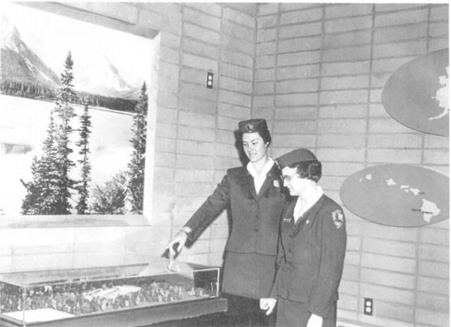 Two women in uniform, at the Grand Canyon Training Center pointing to diorama