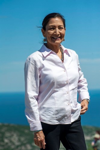 Deb Haaland, standing at Acadia National Park with ocean behind her