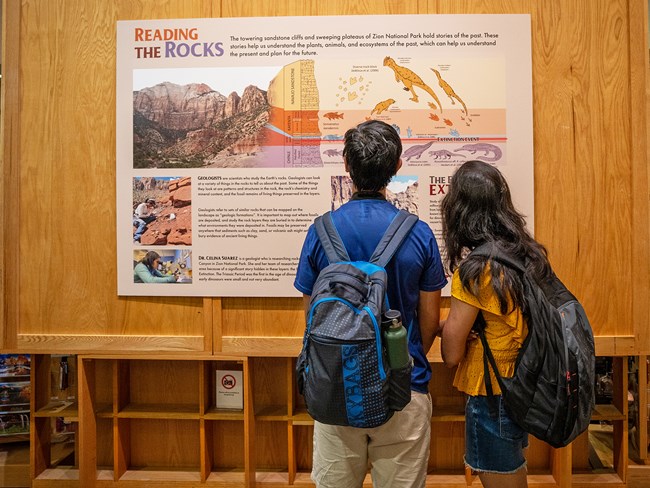 Two people look at a large exhibit panel