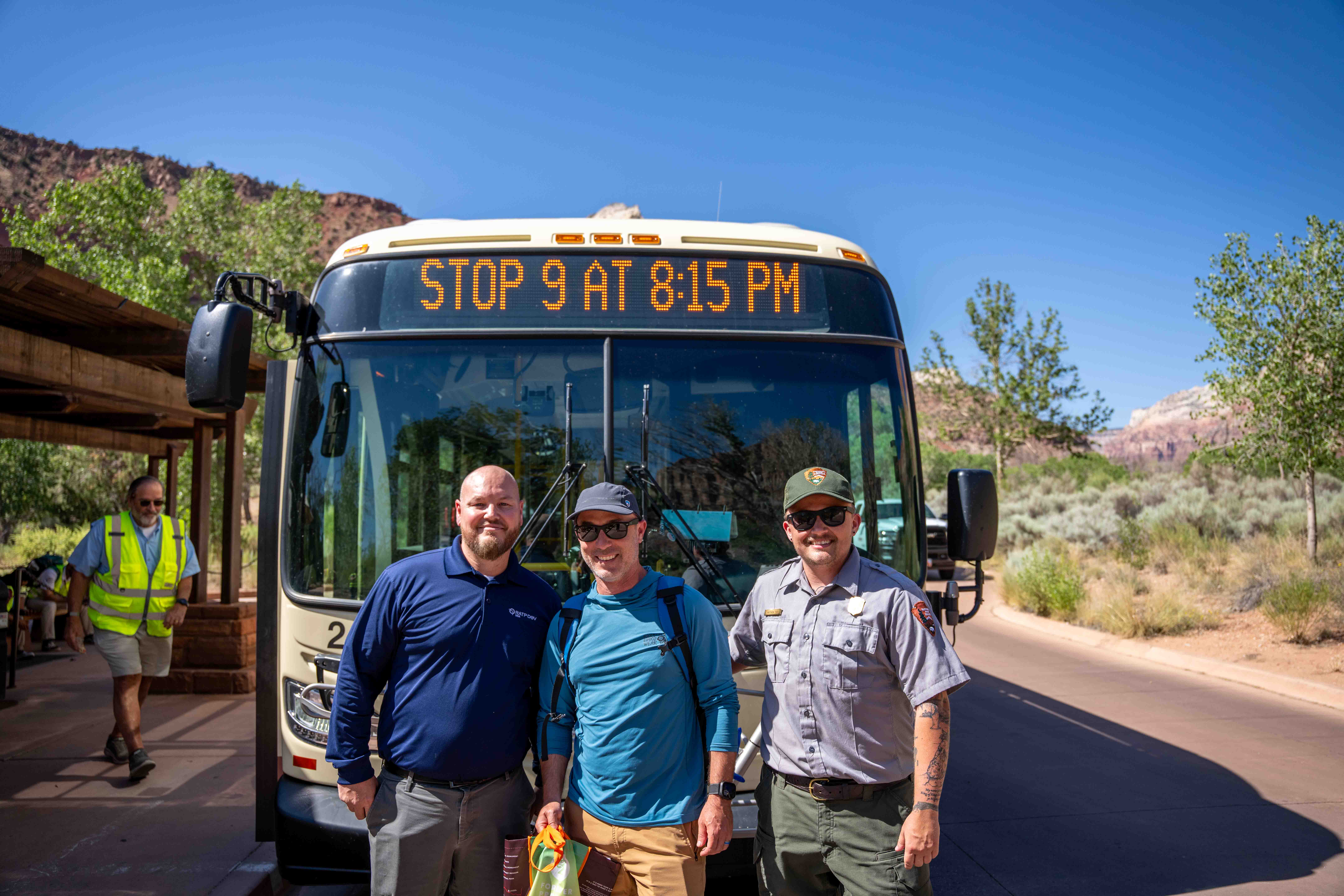 100 millionth shuttle bus rider Three men standing in front of a bus