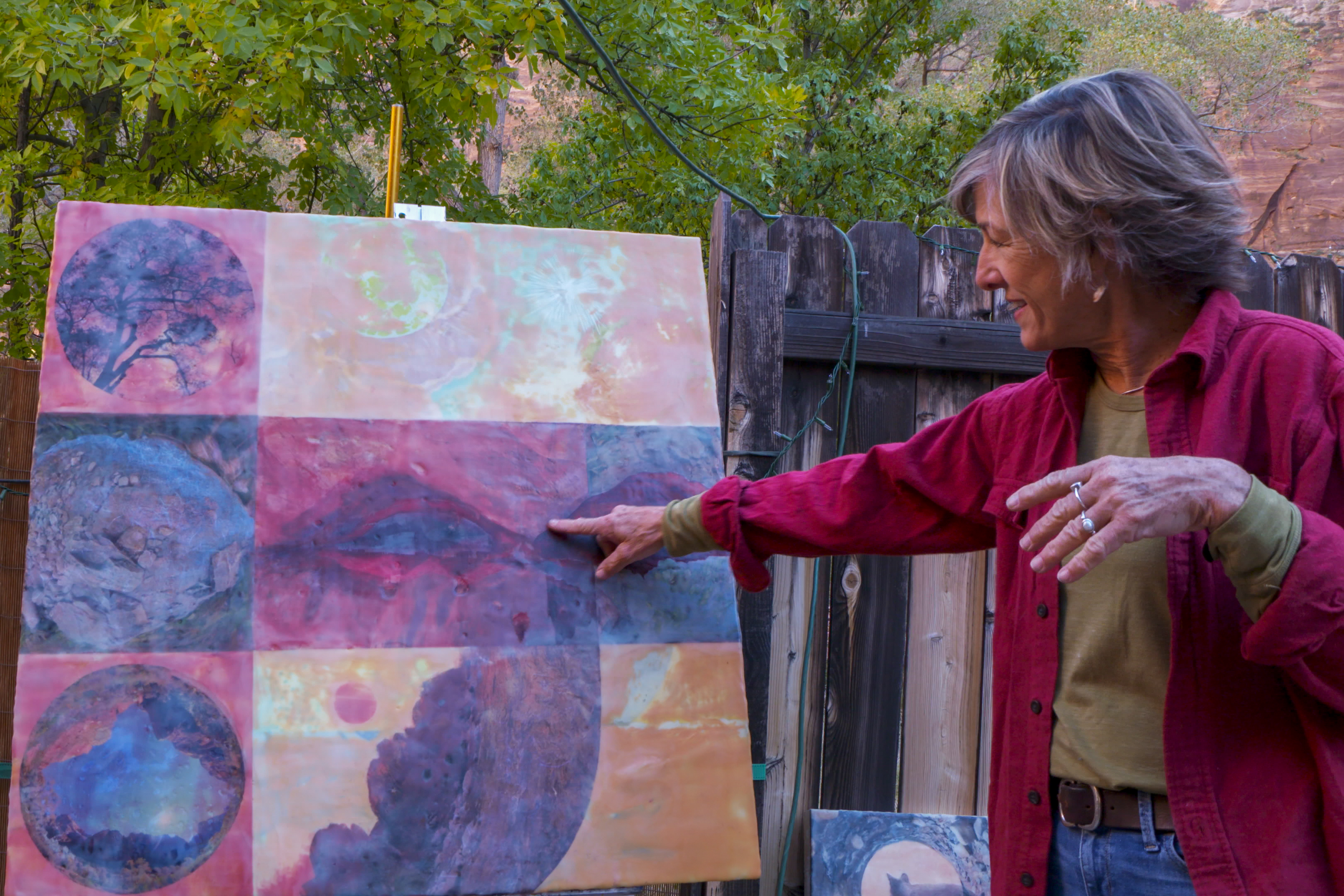 Artist in Residence Alison Green_11072023_1-28 A woman in a red shirt pointing to artwork on a canvas