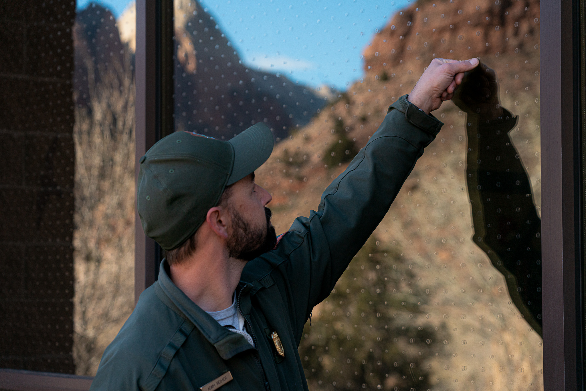 Ranger looks at small plastic dots on building window.