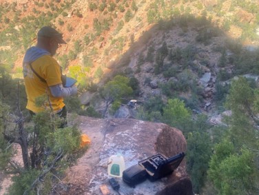 photograph of man operating drone, high over a canyon