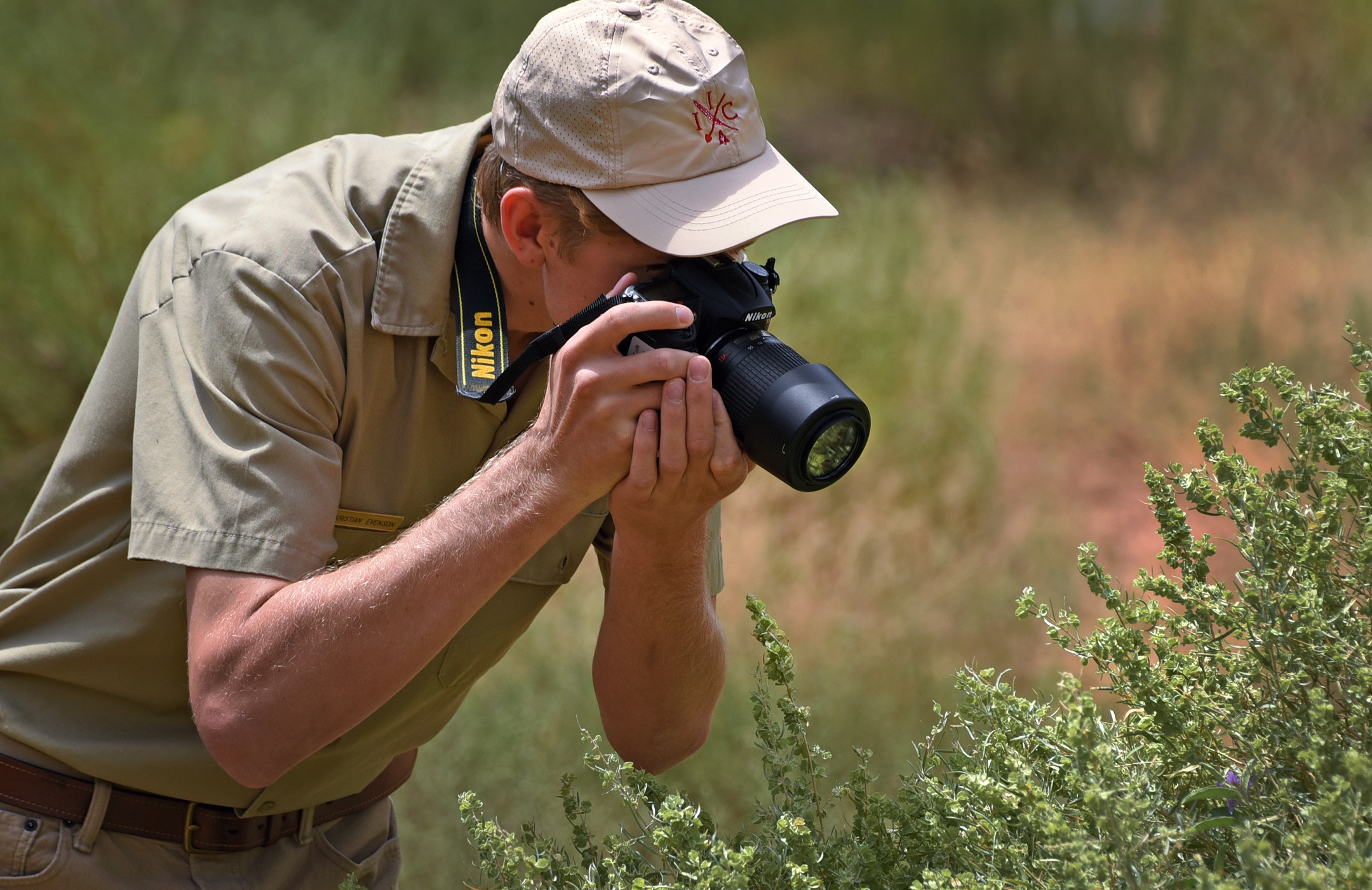 A person wearing a uniform takes a picture of a plant