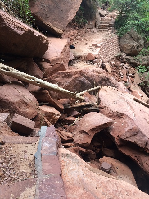 Part of the trail is damaged, covered in rock and debris.