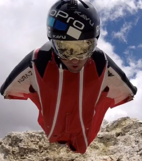 close up view from a helmet cam facing a BASE jumper in a red, white, and blue wingsuit