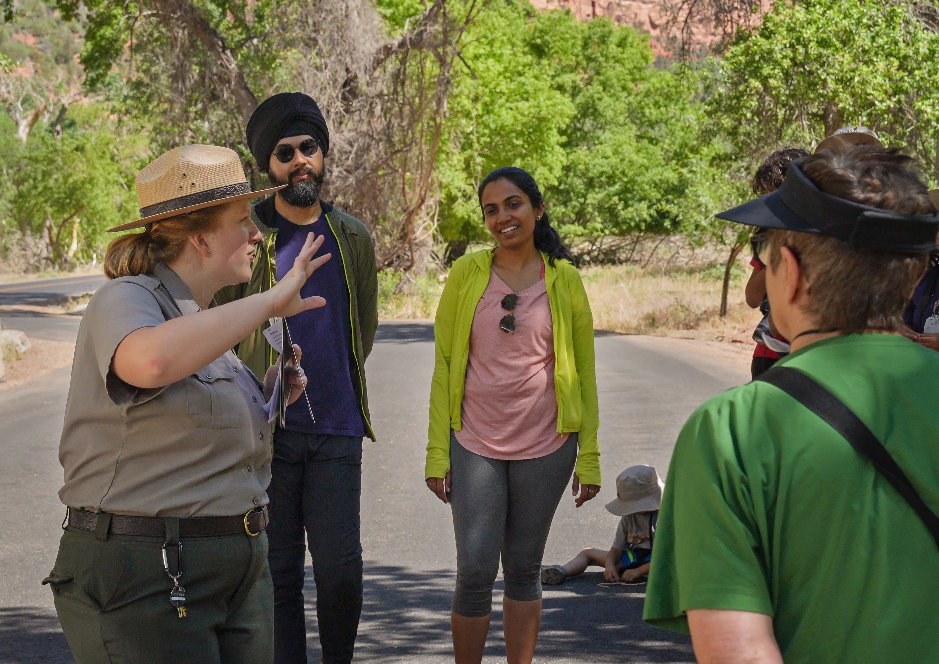 Park Ranger Program A park ranger talking to visitors at a road pullout with greenery and red sandstone in teh background